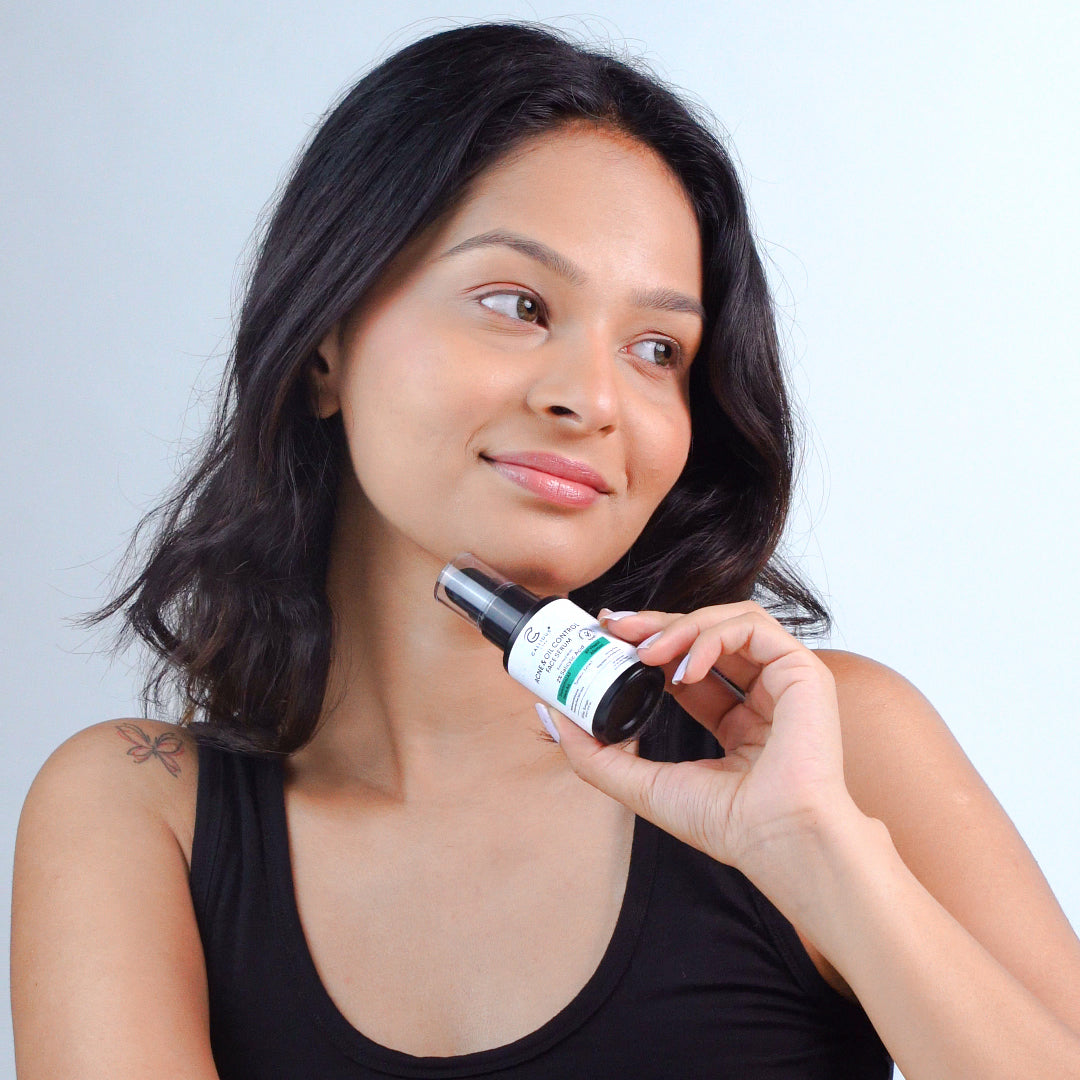 Woman holding a bottle of skincare product against a plain background