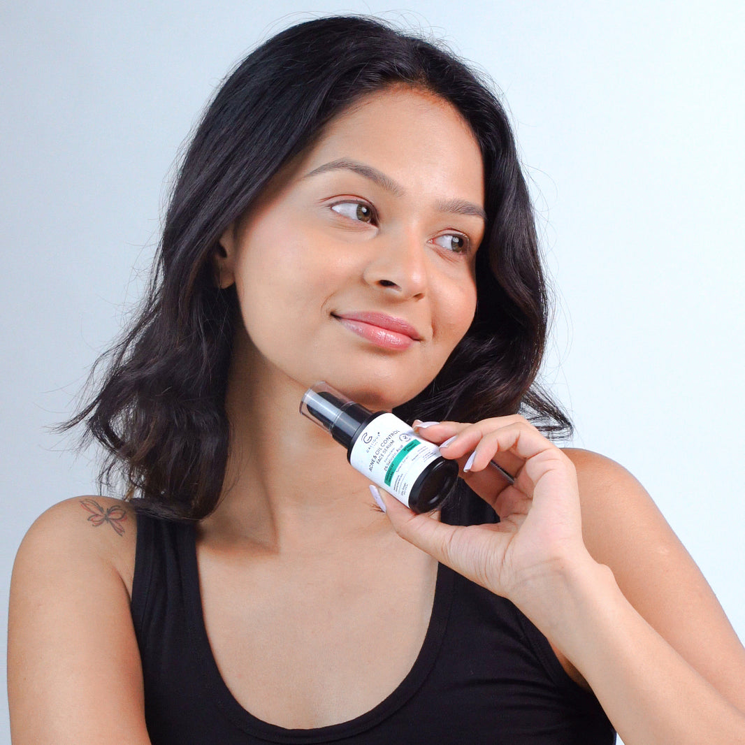 Woman holding a bottle of skincare product against a plain background