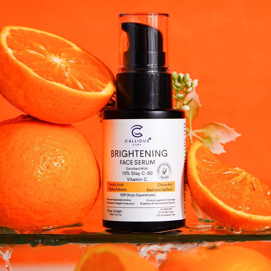 Brightening Face Serum by Callidus Care placed with fresh orange slices on an orange background.