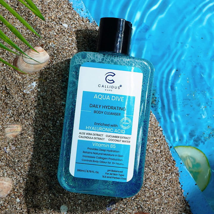 Callidus Care Aqua Dive Body Cleanser bottle on sand by poolside with seashells.