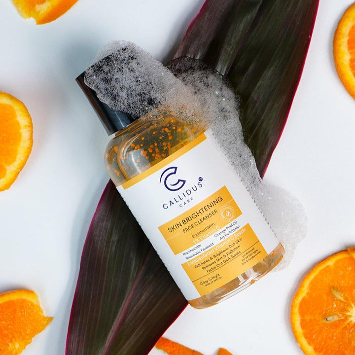Callidus Care Skin Brightening Face Cleanser with Vitamin C and Orange Peel Oil, surrounded by fresh orange slices and foam for a refreshing skincare routine
